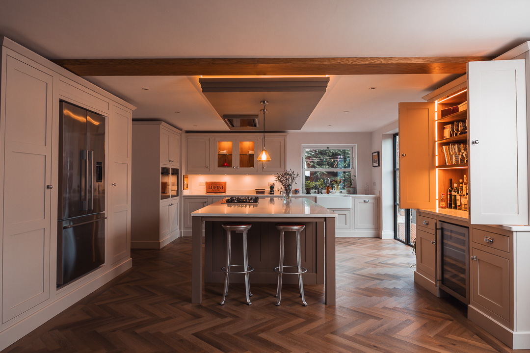 Bespoke in-frame shaker kitchen with central island, oak herringbone floor and illuminated bar area — Hafferty Interiors