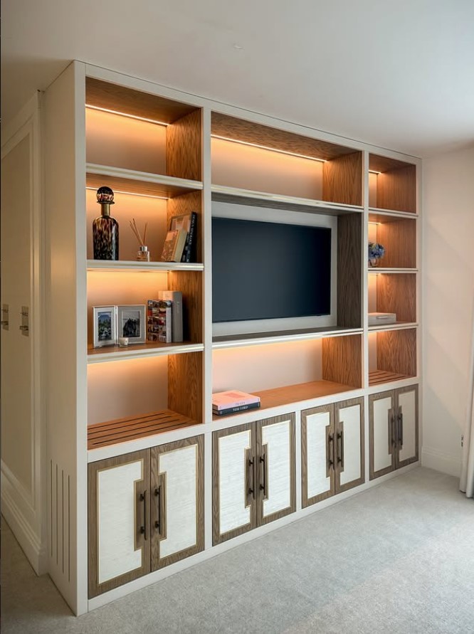 Bespoke fitted bedroom media unit with cream frame, oak backing and fabric-textured door panels — Hafferty Interiors